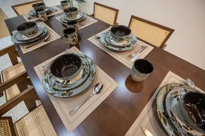 a wooden table with plates and bowls on it at De Luma TheRumah 5 bedroom 3 bathroom in Bukit Mertajam