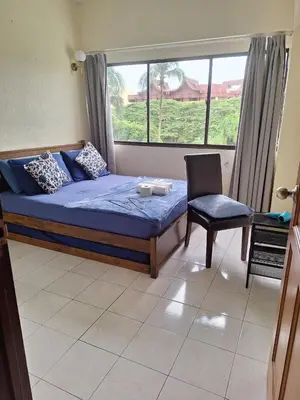 a bedroom with a bed and a chair and a window at Seaput Homes in Ayer Itam