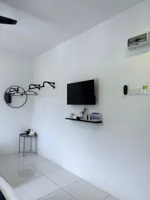 a white room with a tv on a white wall at TDOZE Hotel in Brinchang
