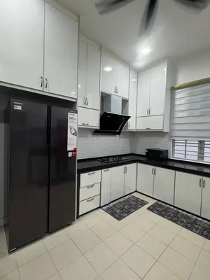 a kitchen with white cabinets and a black refrigerator at Homestay Kakak Adek 3 in Parit Buntar