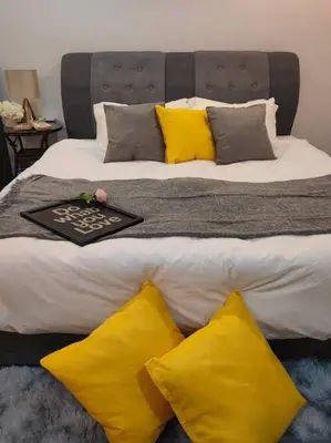 a large bed with yellow pillows and a tray on it at NEW! Spacious 3BR Luxury Stay at Sunrise Gurney GeorgeTown in George Town