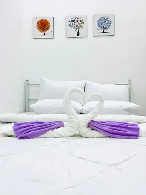 a white bed with purple and white pillows at Syapins Cozy Haven Lunas Homestay Musslim Only in Lunas