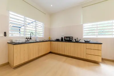 a kitchen with wooden cabinets and a counter top at La Ferringhi Villa by BRB in Batu Ferringhi