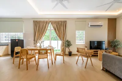 a living room with a table and chairs and a television at La Ferringhi Villa by BRB in Batu Ferringhi
