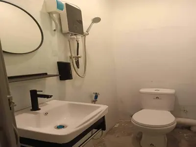 a bathroom with a white toilet and a sink at Hotel O J Stay Guesthouse in Jelutong