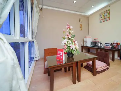 a room with a table with a vase of flowers on it at Hotel O J Stay Guesthouse in Jelutong
