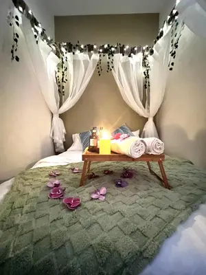 a bedroom with a bed with a table with a candle at Stylish&Affordable Serenity Suite #2min KekLokSi in Ayer Itam