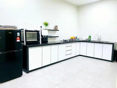 a kitchen with white cabinets and a black refrigerator at D'villa Aryan homestay with private pool in Sungai Petani