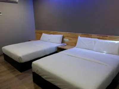 two beds in a hotel room with white sheets at JQ Suria 18 Hotel in Ipoh