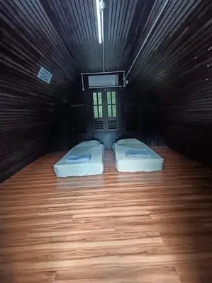 two beds in a dark room with wooden floors at Kuala Woh Resort in Tapah