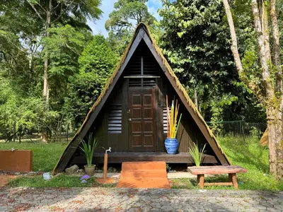 a small house with a door and a bench at Chalet Kuala Woh Resort in Tapah