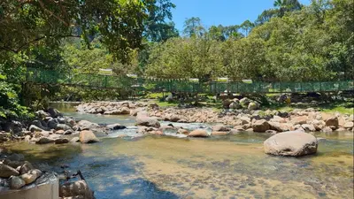a river with rocks and a bridge over it at Chalet Kuala Woh Resort in Tapah