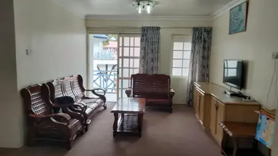 a living room with chairs and a tv and a table at Desa Anthurium Apartment in Tanah Rata