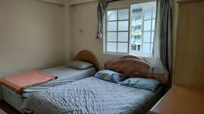 two twin beds in a room with a window at Desa Anthurium Apartment in Tanah Rata
