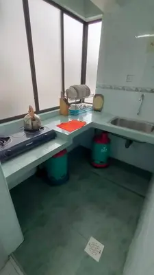 a kitchen with a counter with a sink and a table at Desa Anthurium Apartment in Tanah Rata