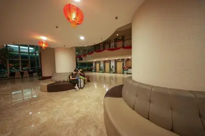 a lobby with two people sitting on couches in a building at Rainbow Paradise with Beach in Tanjung Bungah in Tanjung Bungah