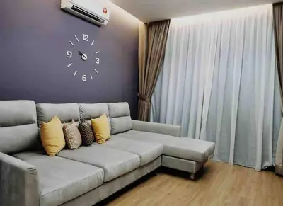 a living room with a couch and a clock on the wall at Batu Ferringhi Home Near Beach in Penang in Batu Ferringhi