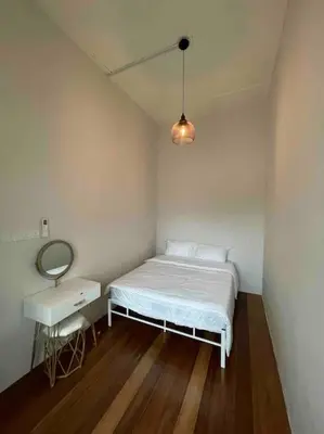 a small white bedroom with a bed and a mirror at Modern Victorian Homestay in George Town