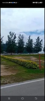 a road with a field of grass and trees at Lumut Marina in Lumut