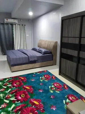 a bedroom with a bed and a blue rug with flowers at Homestay Lyn Impian in Tanjung Rambutan