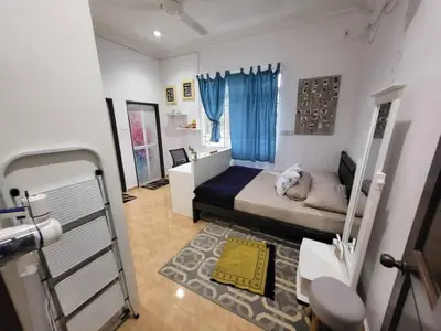 a small bedroom with a bed and blue curtains at Sri MaLati Homestay and Event Space in Balik Pulau