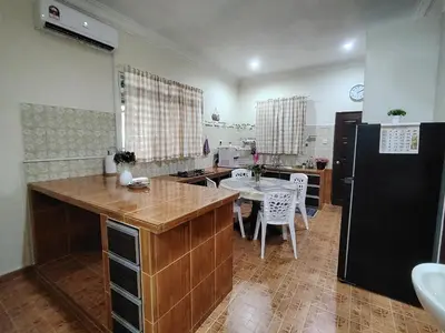 a kitchen with a table and a black refrigerator at Sri MaLati Homestay and Event Space in Balik Pulau
