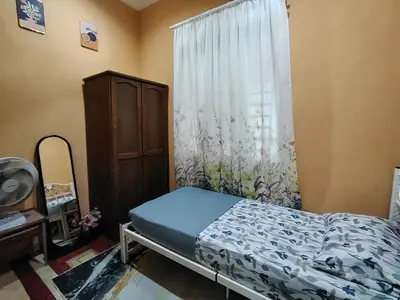 a bedroom with a bed and a window at Sri MaLati Homestay and Event Space in Balik Pulau