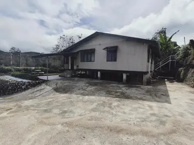 a small white house with a gravel driveway at Rizkie homestay in Tanah Rata