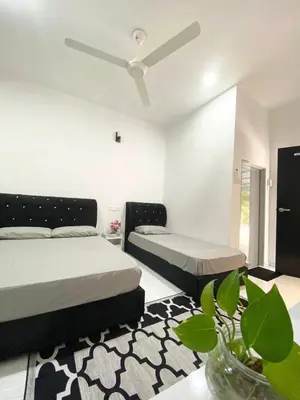 a bedroom with two beds and a table with a plant at ROOMSTAY KOME Merapoh in Perhentian Merapuh Baharu