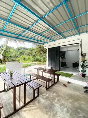 a patio with two picnic tables under a roof at ROOMSTAY KOME Merapoh in Perhentian Merapuh Baharu