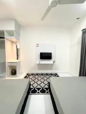 a white room with two beds and a tv at ROOMSTAY KOME Merapoh in Perhentian Merapuh Baharu
