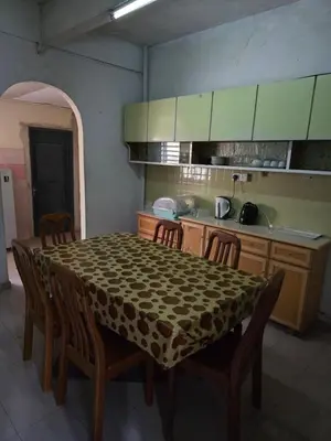 a kitchen with a table and chairs and a kitchen with green cabinets at 3999 Sejahtera Homestay in Lunas