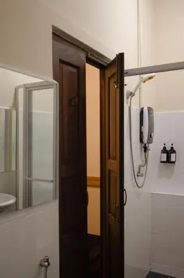 a bathroom with a wooden door and a mirror at Armenian House by IIP in George Town