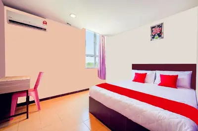 a bedroom with a bed with red pillows and a desk at CMN Hotel & Homestay in Sungai Petani