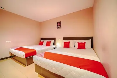 two beds in a room with red and white at CMN Hotel & Homestay in Sungai Petani