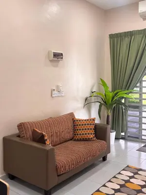 a brown couch in a living room with a plant at Lodging Mak Endon in Seri Manjung