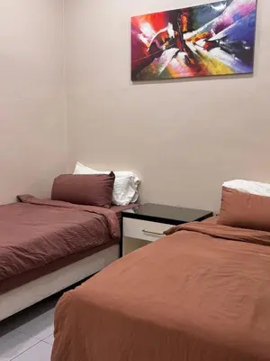 a room with two beds and a painting on the wall at Lodging Mak Endon in Seri Manjung