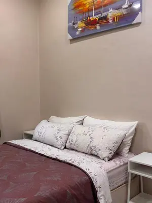 a bed with white pillows and a painting on the wall at Lodging Mak Endon in Seri Manjung