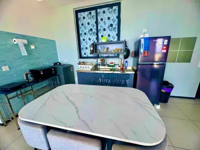 a kitchen with a table and a refrigerator at cozy 3BR family suites 10pax in Jelutong