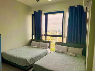 a bedroom with two beds and a window with blue curtains at cozy 3BR family suites 10pax in Jelutong
