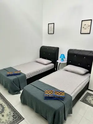 a room with two beds and a table at Pitaloka The Lakes Homestay in Batu Gajah