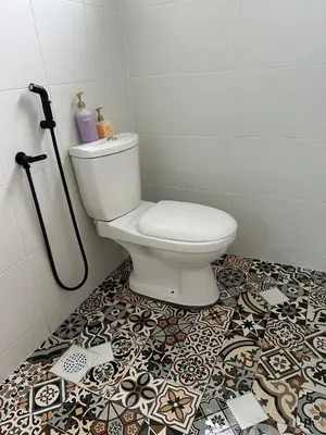 a bathroom with a toilet and a tile floor at Pitaloka The Lakes Homestay in Batu Gajah