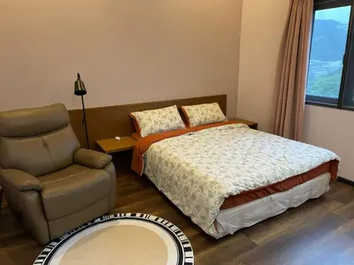 a bedroom with a bed and a chair and a mirror at GreenValley in Brinchang