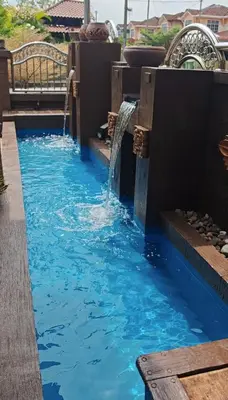 a water feature in a pool with a waterfall at Homestay Santai Bertam in Kepala Batas