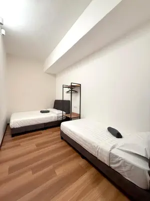 two beds in a room with white walls and wooden floors at Sofu Inn in Jelutong