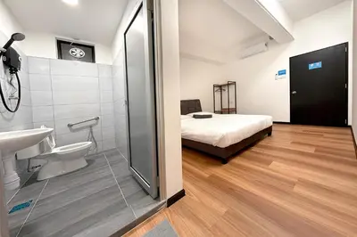 a bathroom with a shower and a sink and a bed at Sofu Inn in Jelutong