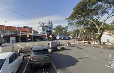 a street with cars parked in a parking lot at Sofu Inn in Jelutong