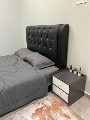 a bed with a black headboard and a night stand at Rimbunan Padi Roomstay in Bagan Serai
