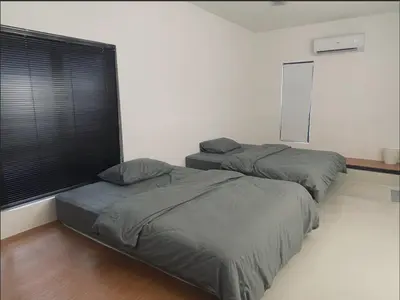 a bedroom with two beds and a window with black blinds at 39 Haus in Bukit Mertajam
