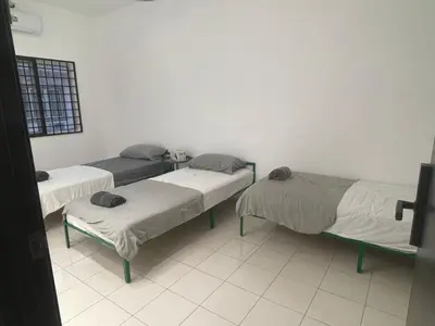 a room with two beds and a table in it at 39 Haus in Bukit Mertajam